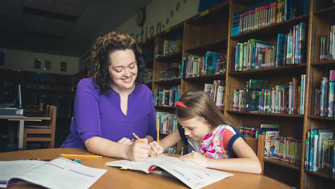 A teacher teaching a student in a classroom.