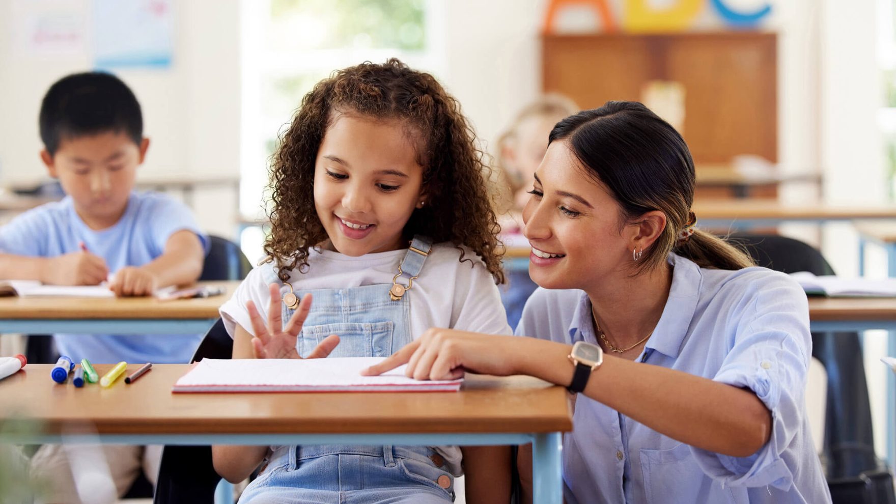 Teacher helping a student in a classroom.