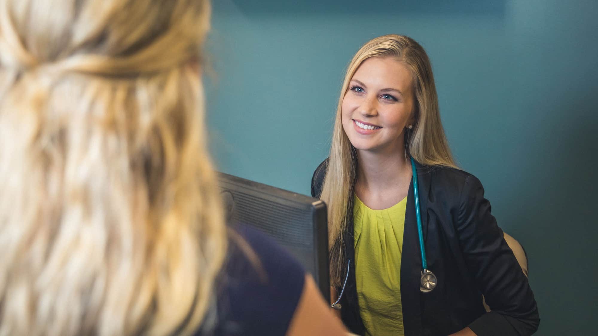 A nurse smiles as she meets with a patient. Earn your medical and health services management position with a degree from Regent University.