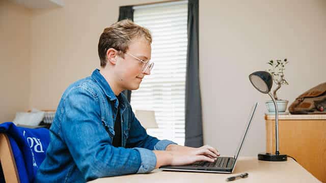 A Regent University student working on his laptop.