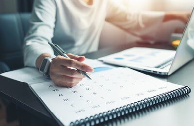 A student writing their life coaching appointment on a calendar at Regent University, a Christian college in Virginia Beach.