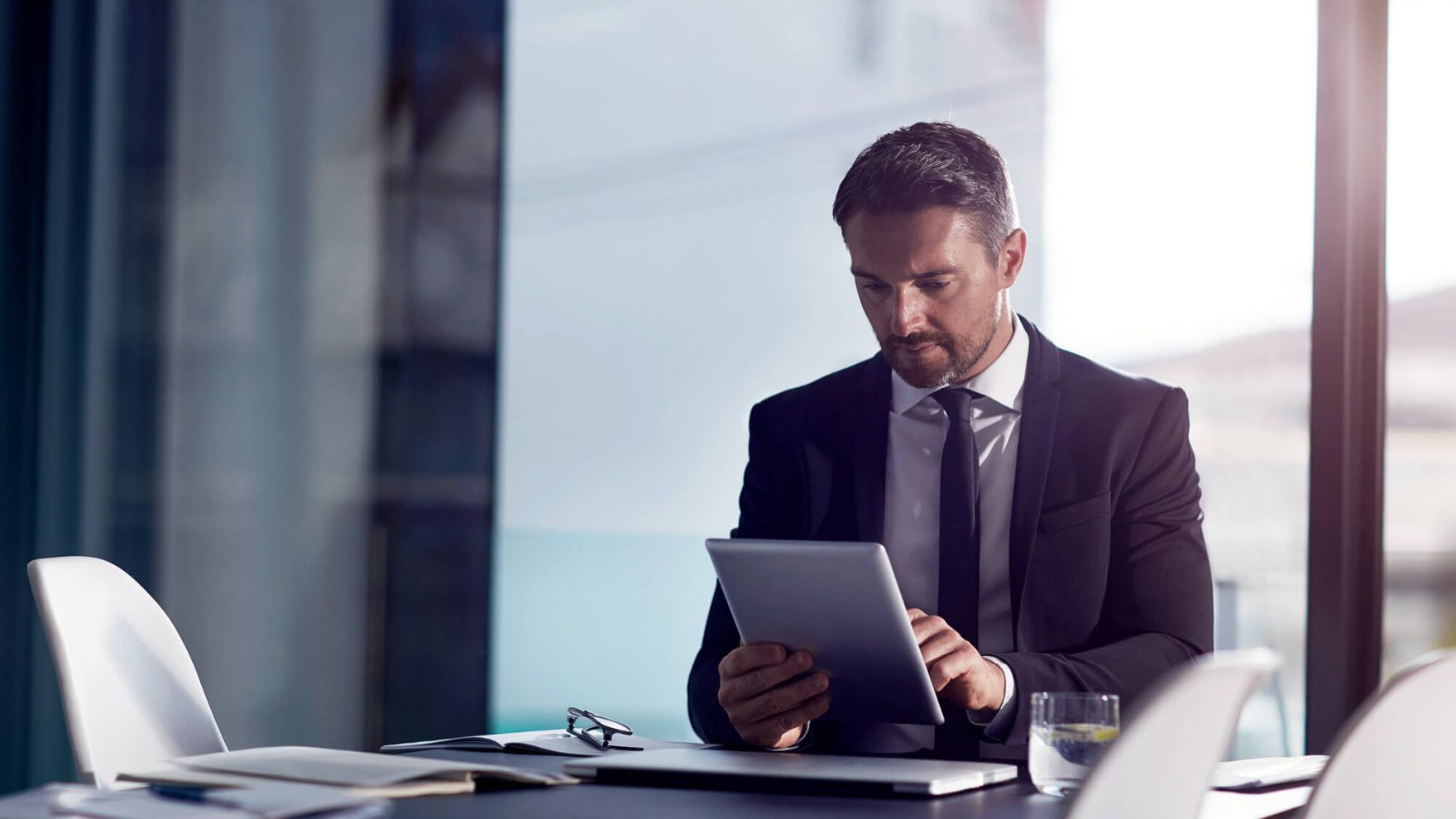 Businessman looking at a tablet: Learn more about Regent's fully online DBA in Finance and Investing program.